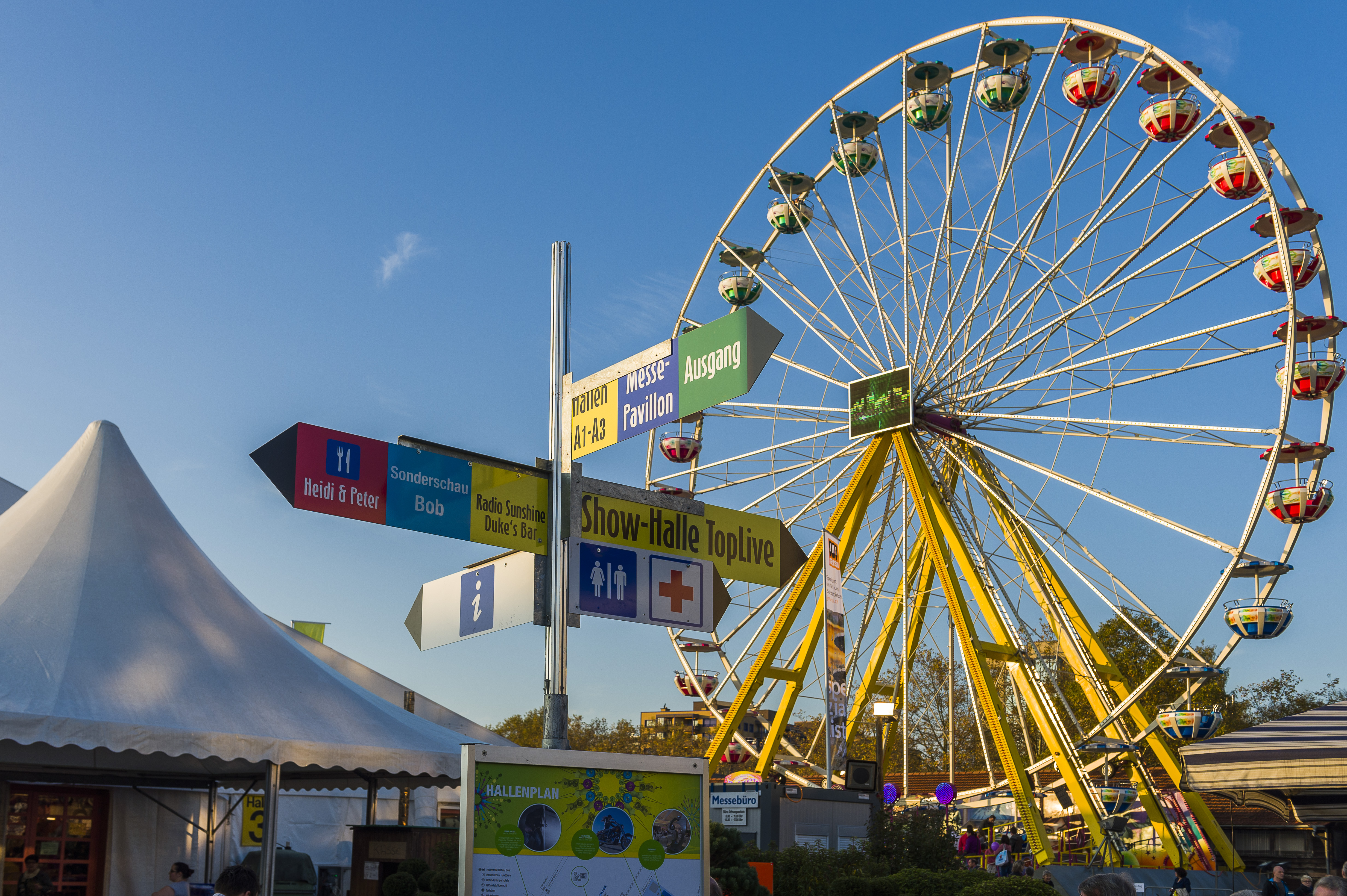 Gelbes Riesenrad im Vordergund und Zelte im Hintergrund